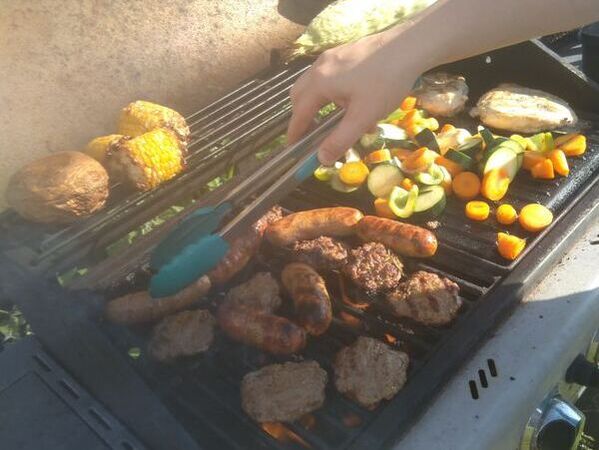 Picture of a bbq grill with a variety of meats and vegetables cooking.